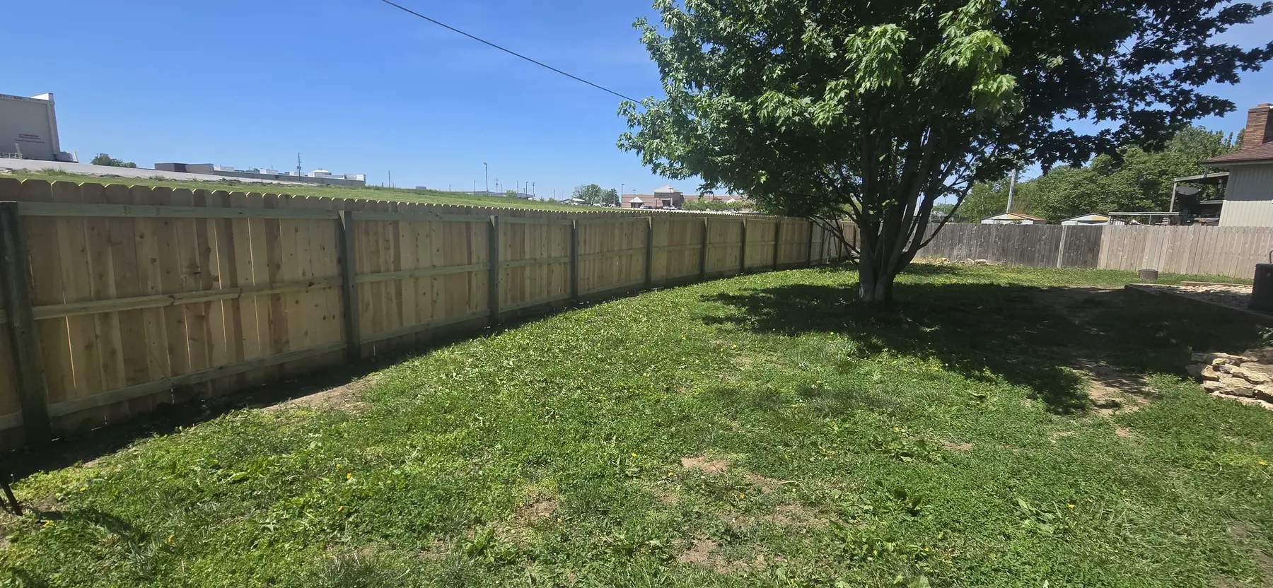 Finished cedar privacy fence surrounding a backyard in Belton, Missouri