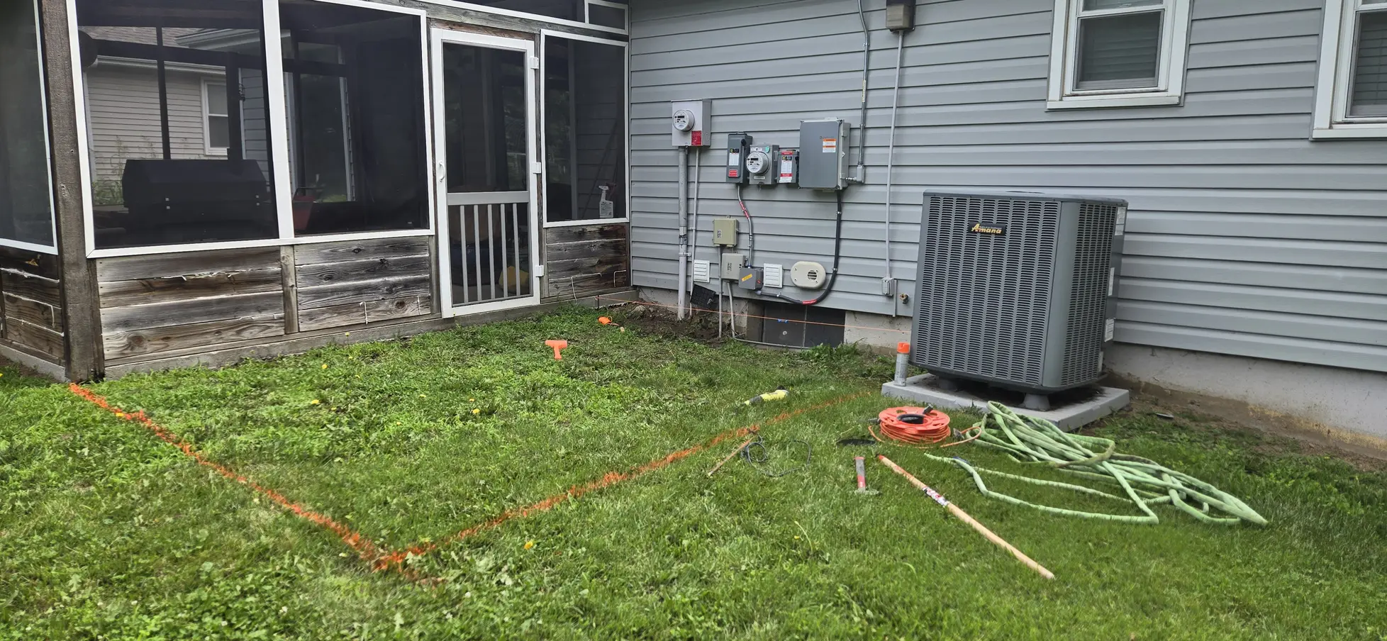 Marked patio footprint in the lawn beside a screened porch before construction