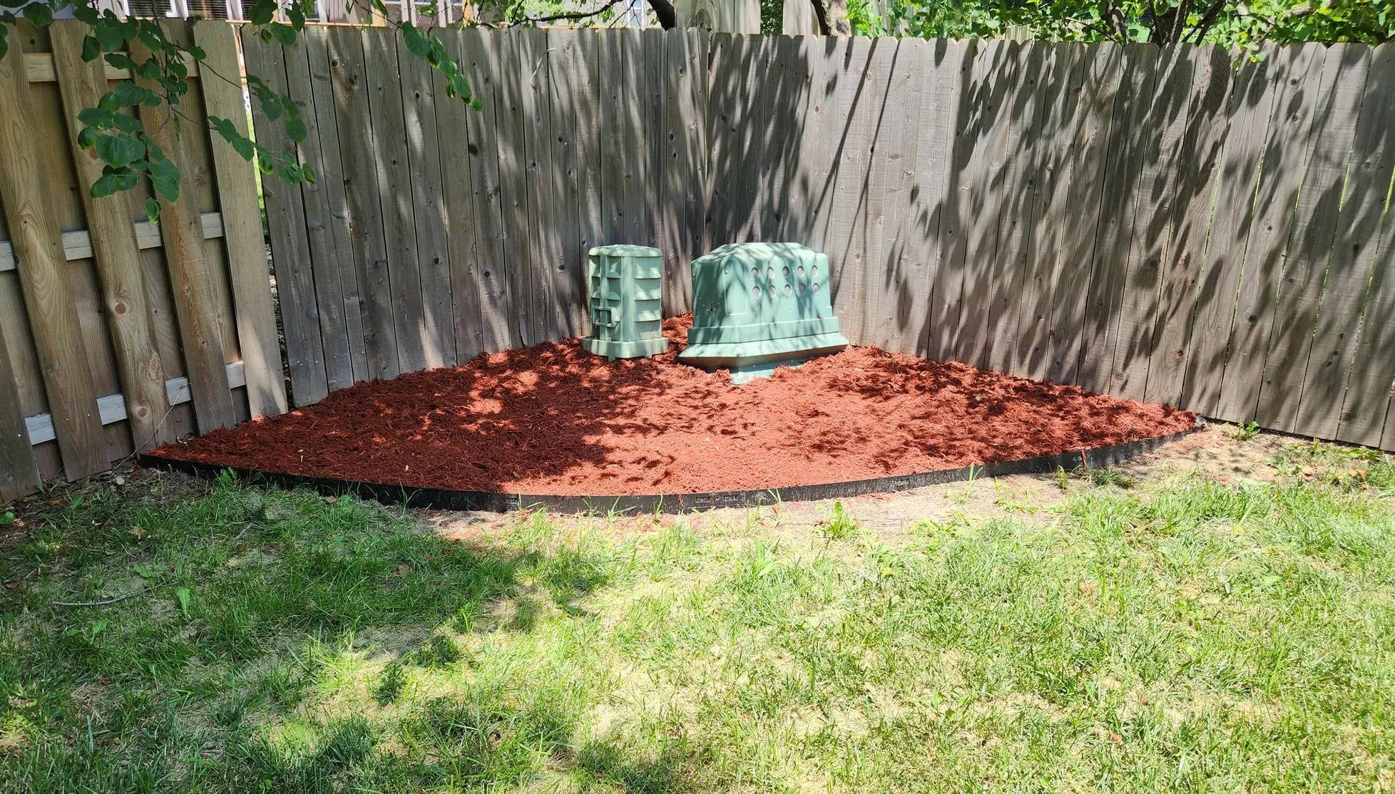 New red mulch bed with black metal edging around utility equipment